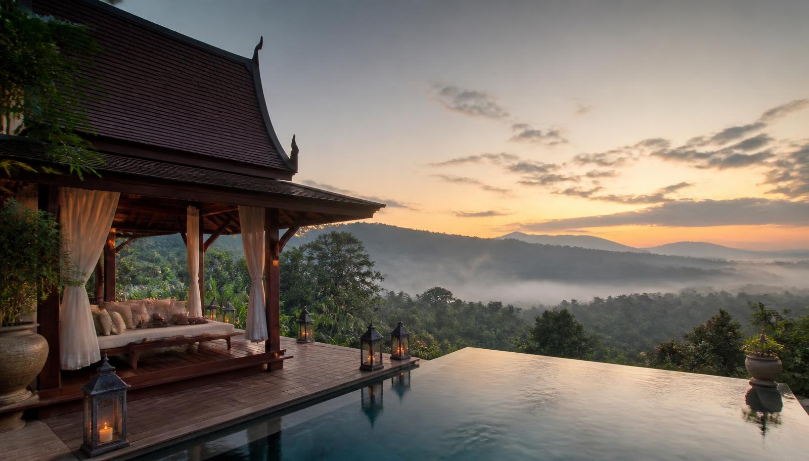 Thai teak wellness pavilion at dawn above a misted jungle valley, infinity pool and lanterns — private retreat villa in northern Thailand